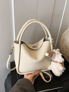 Sac seau chic en cuir beige avec breloque chiot et fermoir rotatif en métal argenté