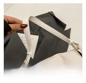 Detail of white lychee grain leather handbag featuring a golden cross-turn lock and wide strap