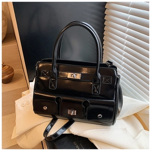 Détail du sac à main noir brillant avec boucles argentées et trois poches décoratives