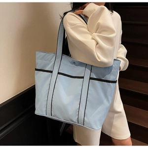 Detailed view of spacious light blue tote bag with durable black woven straps for daily use