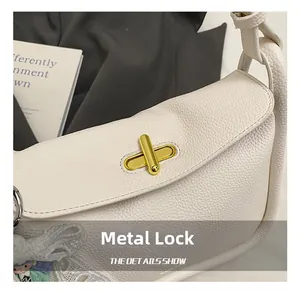 Detailed shot of golden hardware twist lock on off-white lychee grain leather bag