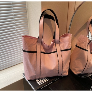 Pink nylon tote bag with black webbing straps and metal snap button closure details