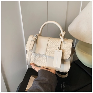 Vue détaillée du sac en cuir crème avec texture tressée et étiquette de mode