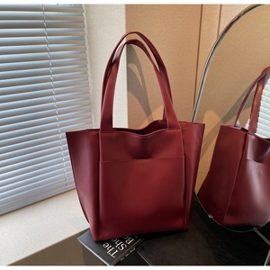Detail view of burgundy leather tote bag featuring sleek outer pocket and dual long straps