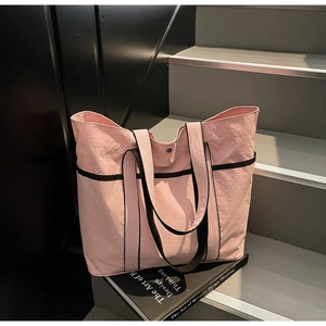 Close-up of pink large capacity nylon tote bag with black straps on a book