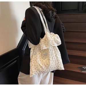 Detailed shot of white floral tote bag with ruffled handles and Magic Pocket woven label