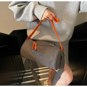 Détail du sac cylindre en toile avec bandoulière orange et broderie bleue 1985 sur le modèle