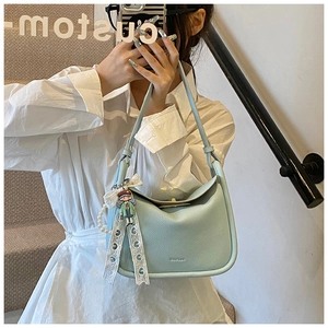 Detail view of light blue lindy-style handbag with cartoon charm and lace ribbon