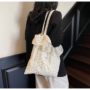 Detail of white floral tote bag featuring plissé fabric and elegant ruffle edges