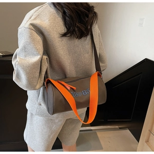 Détail du sac cylindre marron foncé avec bandoulière orange et broderie bleue 1985