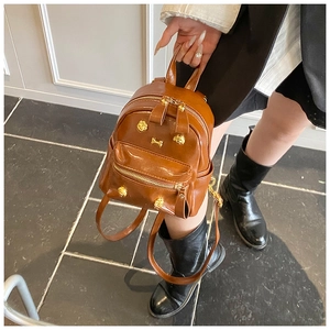 Detailed view of mini brown backpack with gold paw-shaped hardware and adjustable straps