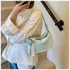 Close-up of mint green litchi texture handbag with creative lace doll charm detail