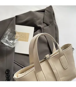 Detail of off-white tote bag with lychee texture and durable handles on grey blazer