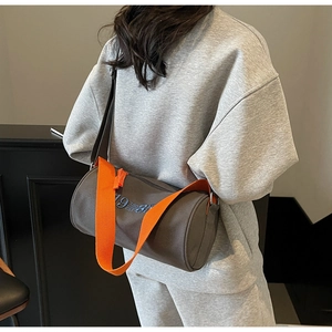 Détail du sac cylindrique gris foncé avec broderie bleue et bandoulière orange