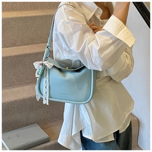Detail of light blue lychee pattern leather bag with lace ribbon and doll pendant