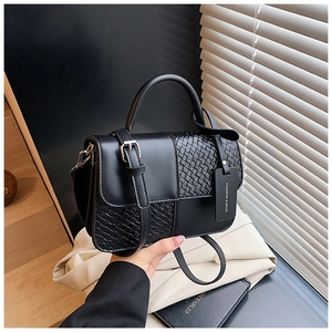 Détail du sac à main noir avec textures mixtes, boucle argentée et étiquette mode