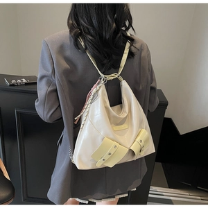 Détail du sac hobo en cuir blanc cassé avec poches à œillets métalliques et pompon tissé