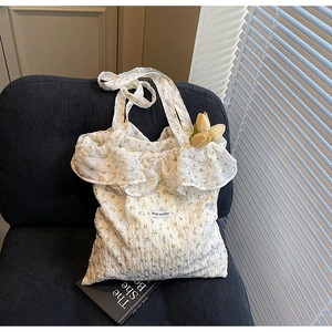 Detail of white floral tote bag with frilled edges and Magic Pocket label on a sofa