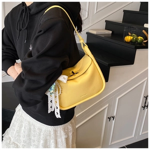 Detail of yellow pebbled leather bag with gold twist lock and pearl lace accessory