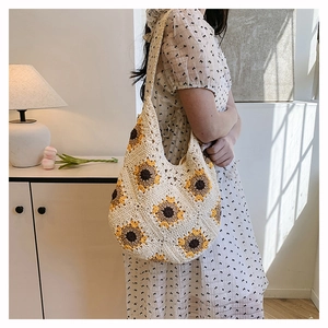 Détail d'un sac hobo en crochet fait main avec motifs de tournesol sur une bandoulière beige