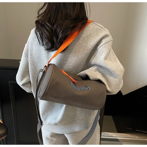 Détail du sac cylindrique en toile grise avec sangle orange et broderie bleue 85
