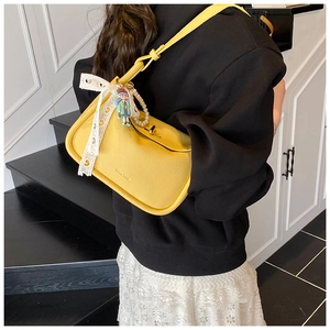 Detail of yellow crossbody bag with pearl charms and lace bow on a female model
