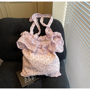 Close-up of lilac floral tote bag with ruffled edges on a velvet sofa with a book