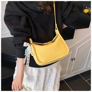 Detail of yellow pebbled leather handbag with lace bow and pearl charm ornament
