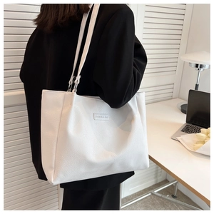 Detail of a minimalist white large tote bag with FASHION & BAG leather tag on textured PU leather