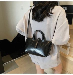 Modern black glossy tote bag with adjustable shoulder strap shown on a model's back