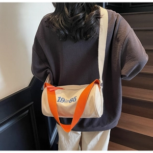 Sac cylindre en toile sur modèle avec sangle orange et graphisme 1985 T.S.D. EST