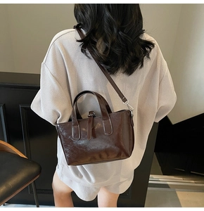 Dark brown leather tote bag detail with decorative buckle and adjustable shoulder strap