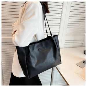 Macro detail of black pebble leather texture and FASHION & BAG logo on the tote bag