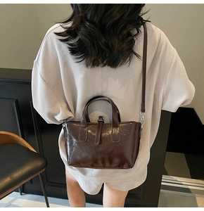 Detail of dark brown glossy leather bucket bag showing adjustable strap and silver hardware