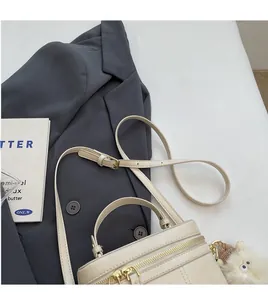 Gros plan du sac beige avec finitions dorées et peluche sur une veste de costume