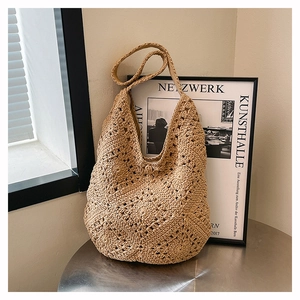 Gros plan du sac hobo en crochet beige avec des motifs tissés sur une table en métal