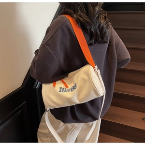 Détail du sac cylindre en toile avec broderie bleue 1985 et bandoulière orange