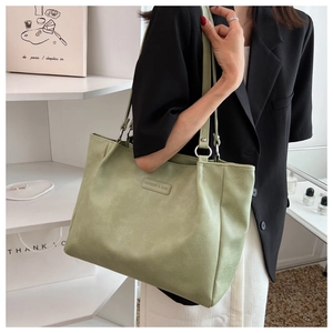 Detail of pistachio green tote bag with silver ring hardware and fashion leather label