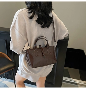 Detailed view of deep coffee glossy patent leather handbag with adjustable cross-body strap