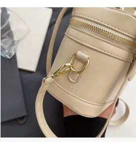 Détail d'un sac seau cylindrique en cuir beige avec fermeture éclair et détails en métal doré