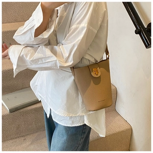 Detail einer khakifarbenen Beuteltasche aus genarbtem Leder mit edlem Goldverschluss