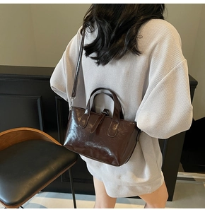 Detail of high-gloss dark brown leather handbag with adjustable shoulder strap and handle