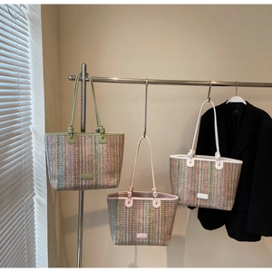 Detail of colorful woven straw tote bags in green, pink, and ivory with vertical textures