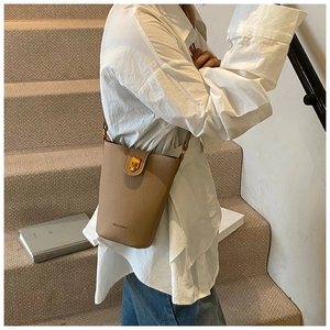 Detail einer braunen Leder-Eimertasche mit Lychee-Muster und goldenem Drehverschluss