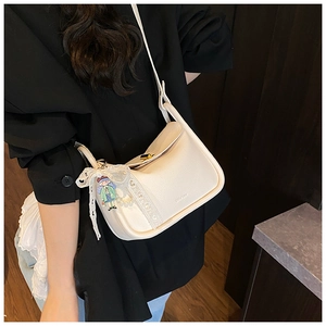 Detail of white litchi pattern leather crossbody bag with lace bow and gold clasp