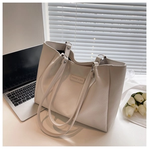 Detail of cream tote bag with litchi grain faux leather and FASHION & BAG embossed label