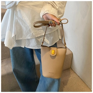 Detail der beigen Beuteltasche aus Leder mit Litschimuster und goldenem Metallschloss