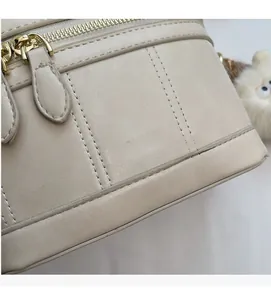 Vue détaillée du sac à main beige en similicuir avec coutures verticales et logo doré