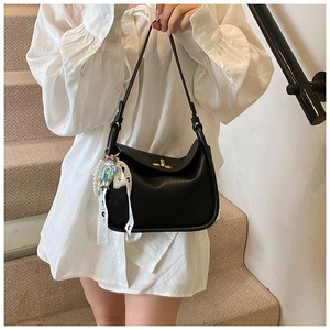 Detail of black lychee grain crossbody bag with golden clasp and pearl charm