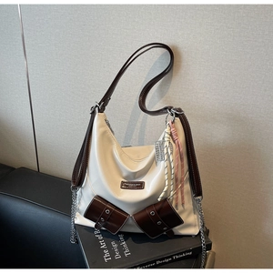 Détail d'un sac cabas blanc avec poches à rabat marron et pendentif en corde tissée